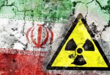 NUCLEAR SURVIVOR: Iran Still Enriching? A cracked wall featuring the Iranian flag and a nuclear warning symbol