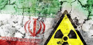 A cracked wall featuring the Iranian flag and a nuclear warning symbol
