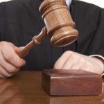 A judge holding a gavel above a wooden block