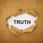 A piece of torn paper revealing the word TRUTH underneath