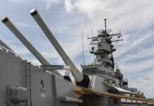 Close-up of a battleships naval guns and superstructure against a cloudy sky
