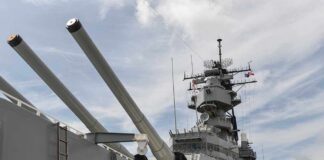 Close-up of a battleships naval guns and superstructure against a cloudy sky