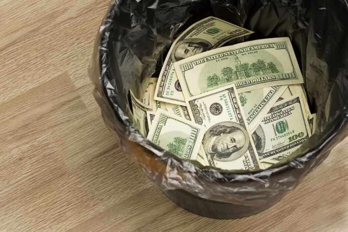 A trash can filled with crumpled hundred dollar bills