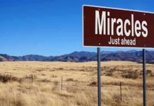 A road sign reading 'Miracles Just ahead' in a desert landscape