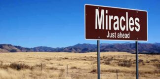 A road sign reading 'Miracles Just ahead' in a desert landscape