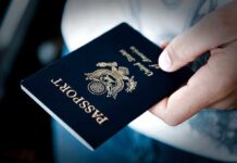 A person holding a United States passport with a dark background
