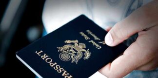 A person holding a United States passport with a dark background
