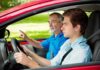 A young man driving a car with an older man giving instructions