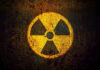 Yellow radiation warning symbol on rusty metal surface.
