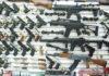 Wall display of various firearms in a store.