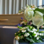 White roses in front of a casket.