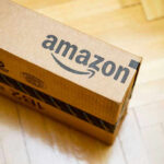 Amazon PRICE-FIXING Exposed — Consumers Crushed Amazon package on wooden floor.