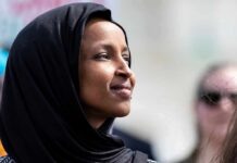 A woman wearing a black hijab looking thoughtfully during an outdoor event