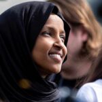 Omar’s Filing Twist–NOBODY’S Buying IT! A woman wearing a black hijab smiling at an outdoor event