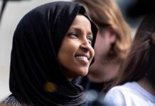 A woman wearing a black hijab smiling at an outdoor event