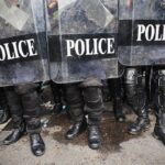 Multiple Shooters UNLEASH Hell at Suburban Park Police officers in riot gear standing behind shields marked POLICE