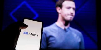 A hand holding a smartphone displaying the Meta logo with a blurred figure in the background
