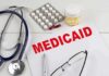 Medical documents with the word Medicaid prominently displayed alongside a stethoscope and medication