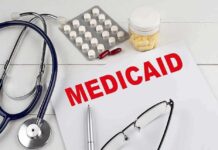 Medical documents with the word Medicaid prominently displayed alongside a stethoscope and medication