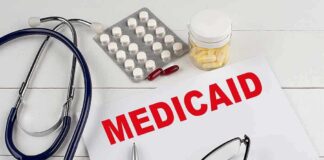 Medical documents with the word Medicaid prominently displayed alongside a stethoscope and medication