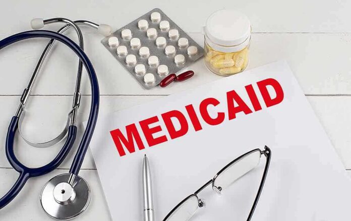 Medical documents with the word Medicaid prominently displayed alongside a stethoscope and medication