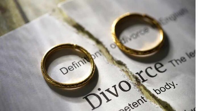 Two wedding rings placed on a torn page with the word Divorce