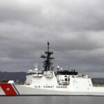 A U.S. Coast Guard ship docked under cloudy skies