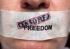Close-up of a persons mouth covered with tape that reads CENSORED FREEDOM