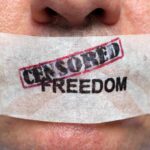 “Stop Journalist” Bill Ignites EXPLOSIVE Firestorm Close-up of a persons mouth covered with tape that reads CENSORED FREEDOM