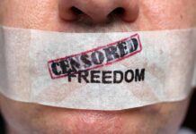 Close-up of a persons mouth covered with tape that reads CENSORED FREEDOM