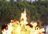 A large explosion with flames and smoke in an outdoor setting