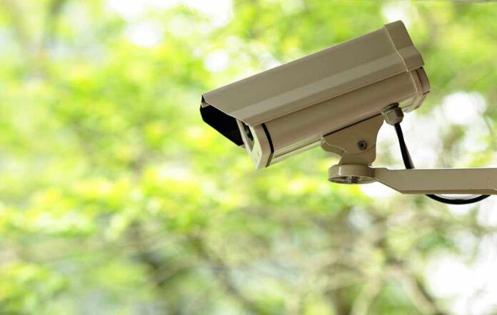 A security camera mounted outdoors with a blurred green background