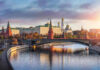 Kremlin by river at sunset with bridge.