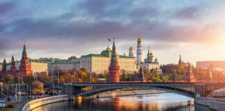 Kremlin by river at sunset with bridge.