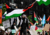 Violent PROTESTERS Shake Manhattan Synagogue Protesters with flags and signs, one holding a megaphone.