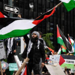 Violent PROTESTERS Shake Manhattan Synagogue Protesters with flags and signs, one holding a megaphone.