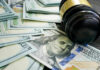 Gavel and hundred dollar bills on table.
