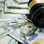 Massive FINES Loom For This STATE’S Employers! Gavel and hundred dollar bills on table.