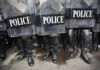Police officers in riot gear holding shields.