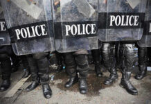 Police officers in riot gear holding shields.