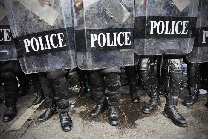 208336891 Police officers in riot gear holding shields.