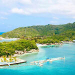 Tito’s EXOTIC Island: Now for EVERYONE Tropical beach with docks and lush green hills.