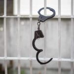 Handcuffs hanging on a barred window.