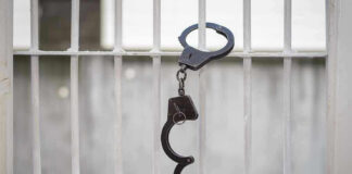Handcuffs hanging on a barred window.