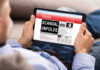 Newsom’s Diaper Deal Sparks $20M Uproar Person reading tablet with headline Scandal Unfolds.