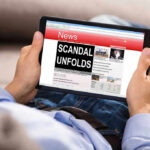 Newsom’s Diaper Deal Sparks $20M Uproar Person reading tablet with headline Scandal Unfolds.