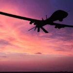 A Battlefield of Swarms, Propaganda, and Rising Global Risks Silhouette of a drone against a colorful sunset.