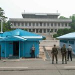 High-Stakes Truce Framework Leaves Major Questions Unanswered Military personnel standing near blue buildings at a border crossing