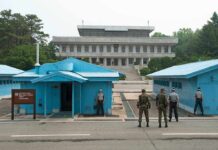 High-Stakes Truce Framework Leaves Major Questions Unanswered Military personnel standing near blue buildings at a border crossing