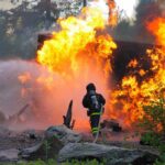Daring Baby Catch: Flames Close In! Firefighter battling a large fire with water spray
